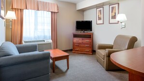 Een hotelkamer met een bank, een houten tafel, een televisie, een kast en een stoel.