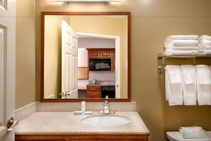 A bathroom with a sink, mirror, and towel rack.