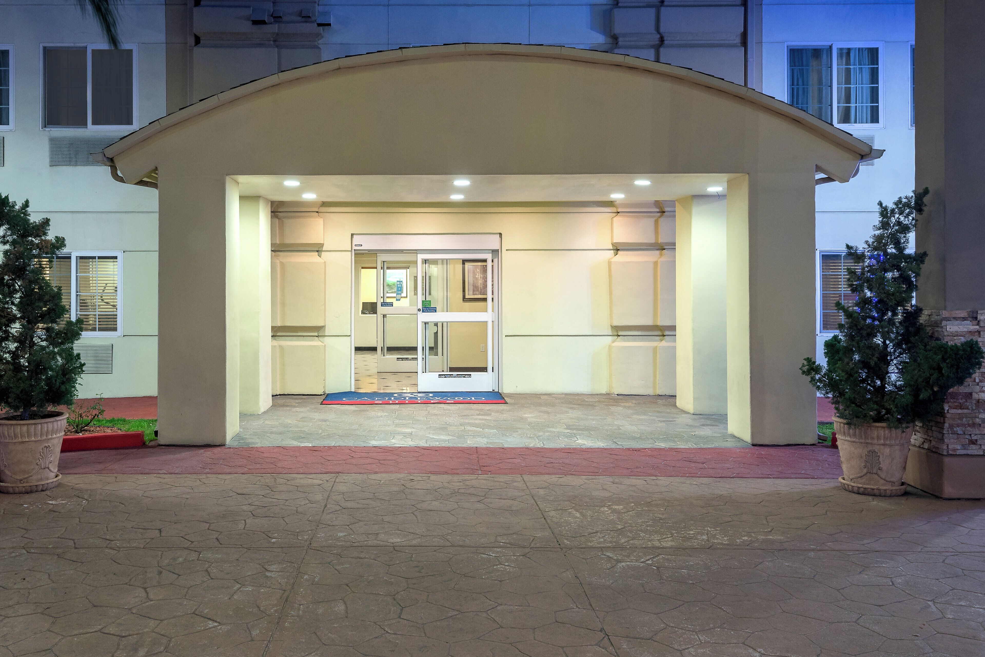A building entrance with a covered porch, a glass door, and a red mat.