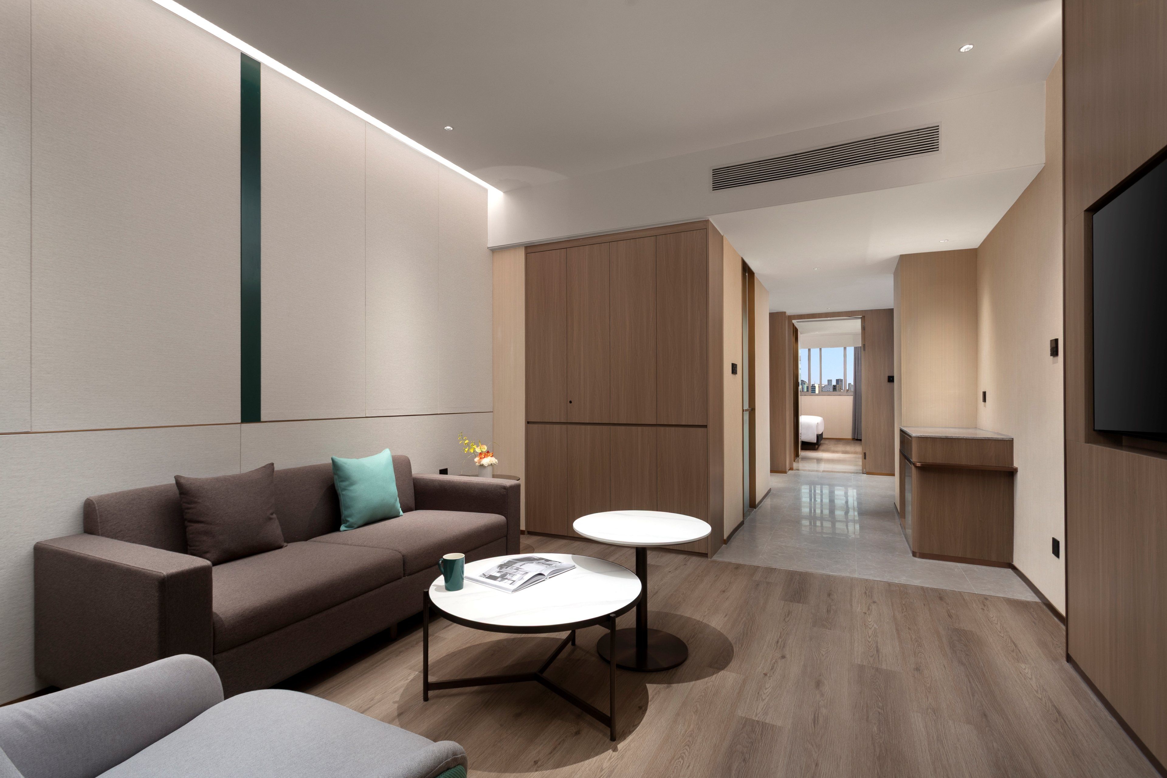 A modern hotel room with a sofa, a small round table, and a TV.