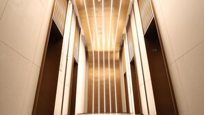 A modern interior with a reflective floor, a central light fixture, and a symmetrical design.