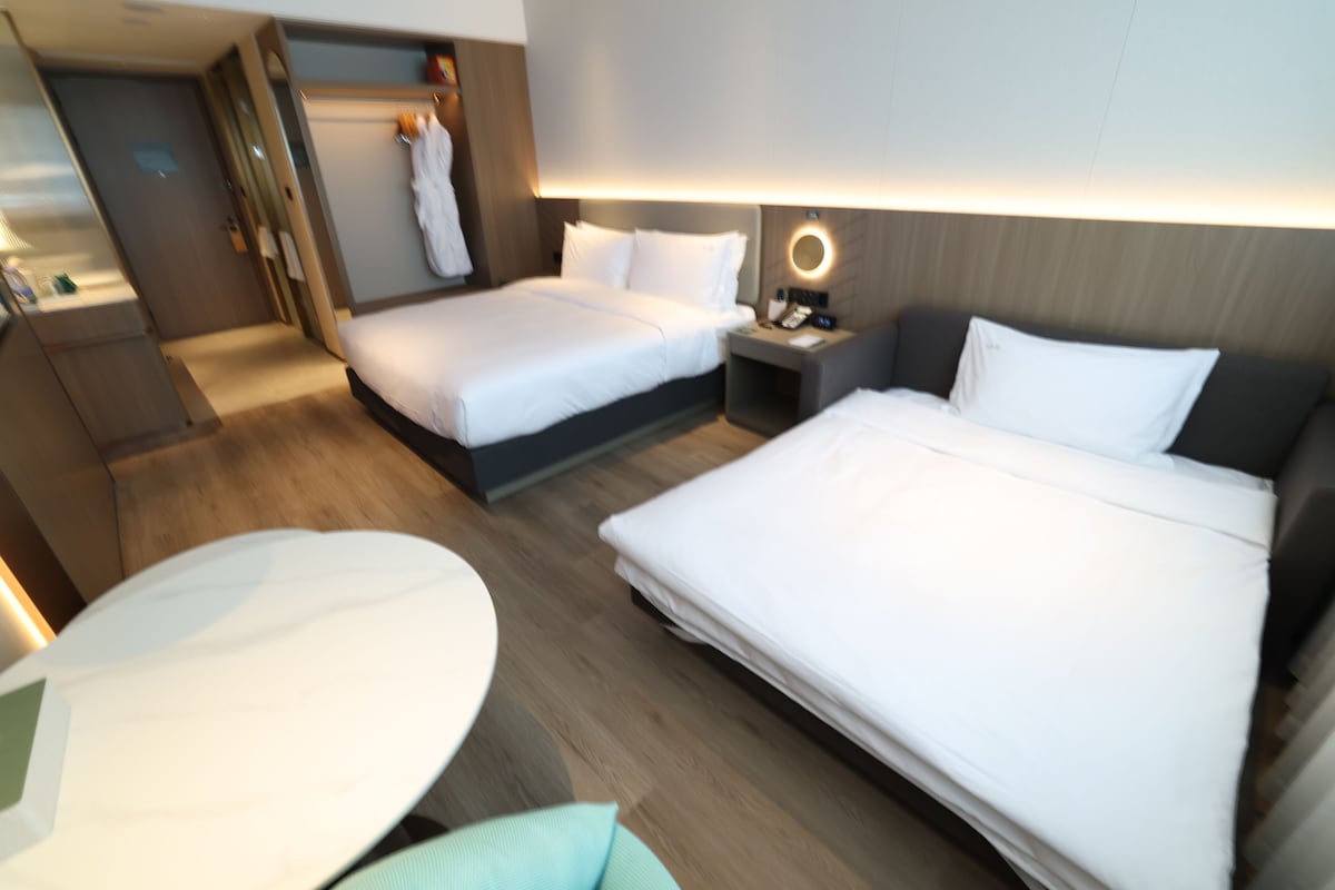 Une chambre d’hôtel avec deux lits, un bureau et une chaise.