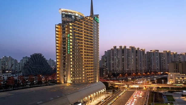 A high-rise hotel with multiple floors, a prominent vertical structure on the side, and a well-lit facade.