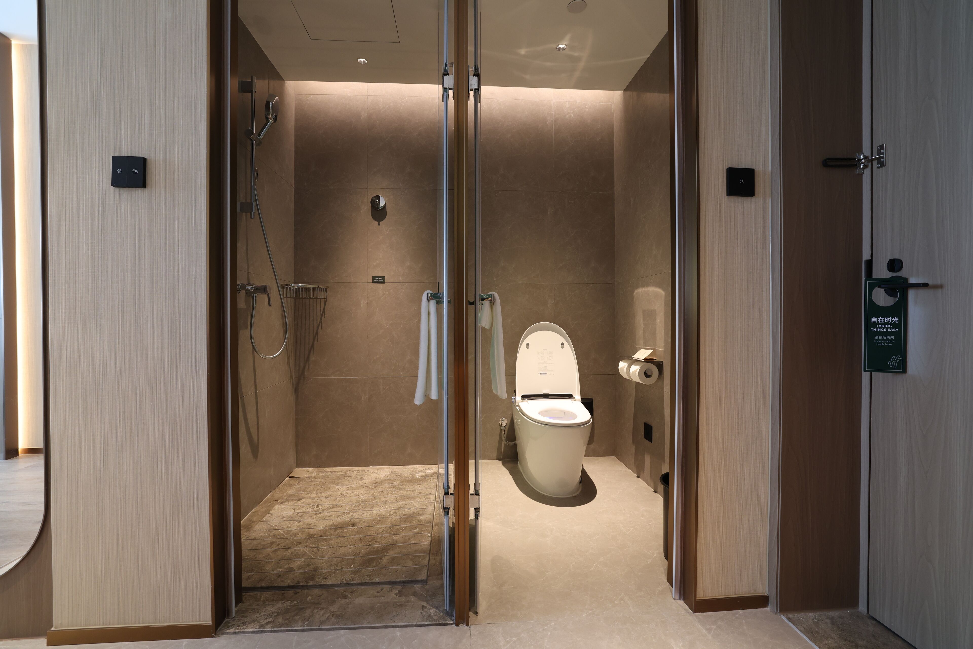 Une salle de bain moderne avec une douche à parois de verre, des toilettes et un porte-serviettes.
