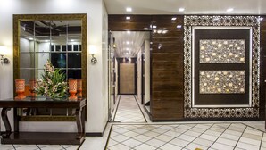 A hotel lobby with a reception desk, a mirror, decorative vases, and a patterned wall. - Hotel Sunstar Heritage (New Delhi)