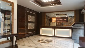 A reception area with a modern design, featuring a reception desk, a decorative wall with a geometric pattern, and a sign that reads "Hotel Sunstar Heritage". - Hotel Sunstar Heritage (New Delhi)