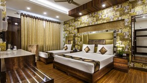 A hotel room with two beds, wooden flooring, a desk, and a vanity with a mirror. - Hotel Sunstar Heritage (New Delhi)