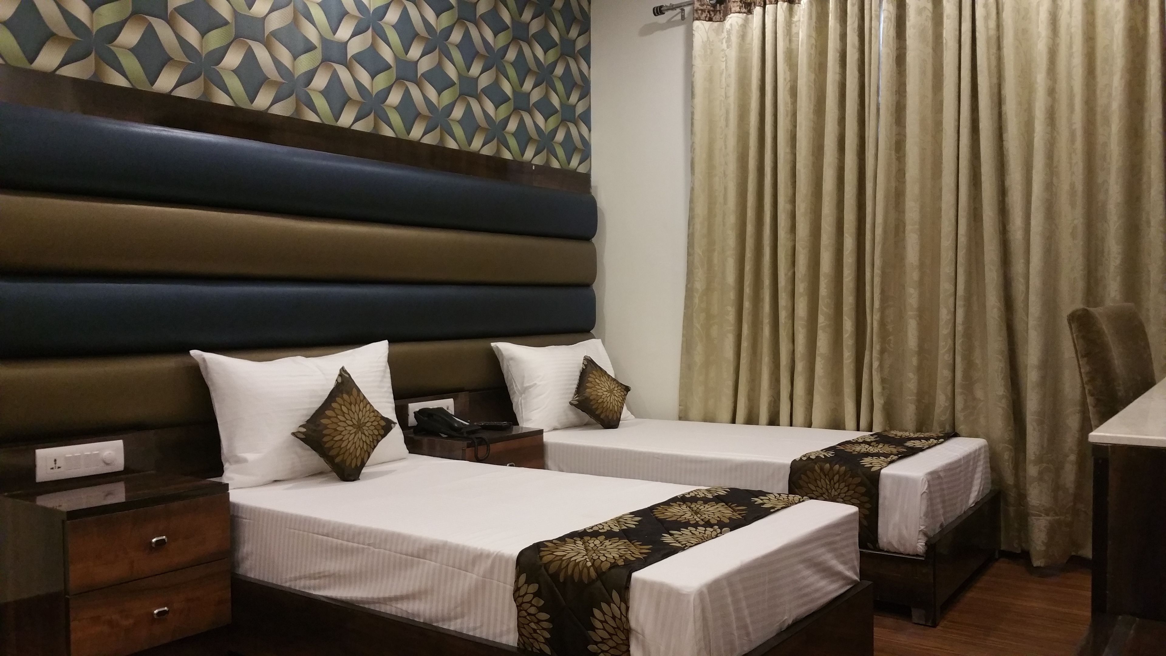 A hotel room with two beds, a headboard, a nightstand, a drawer, a curtain, and a chair.