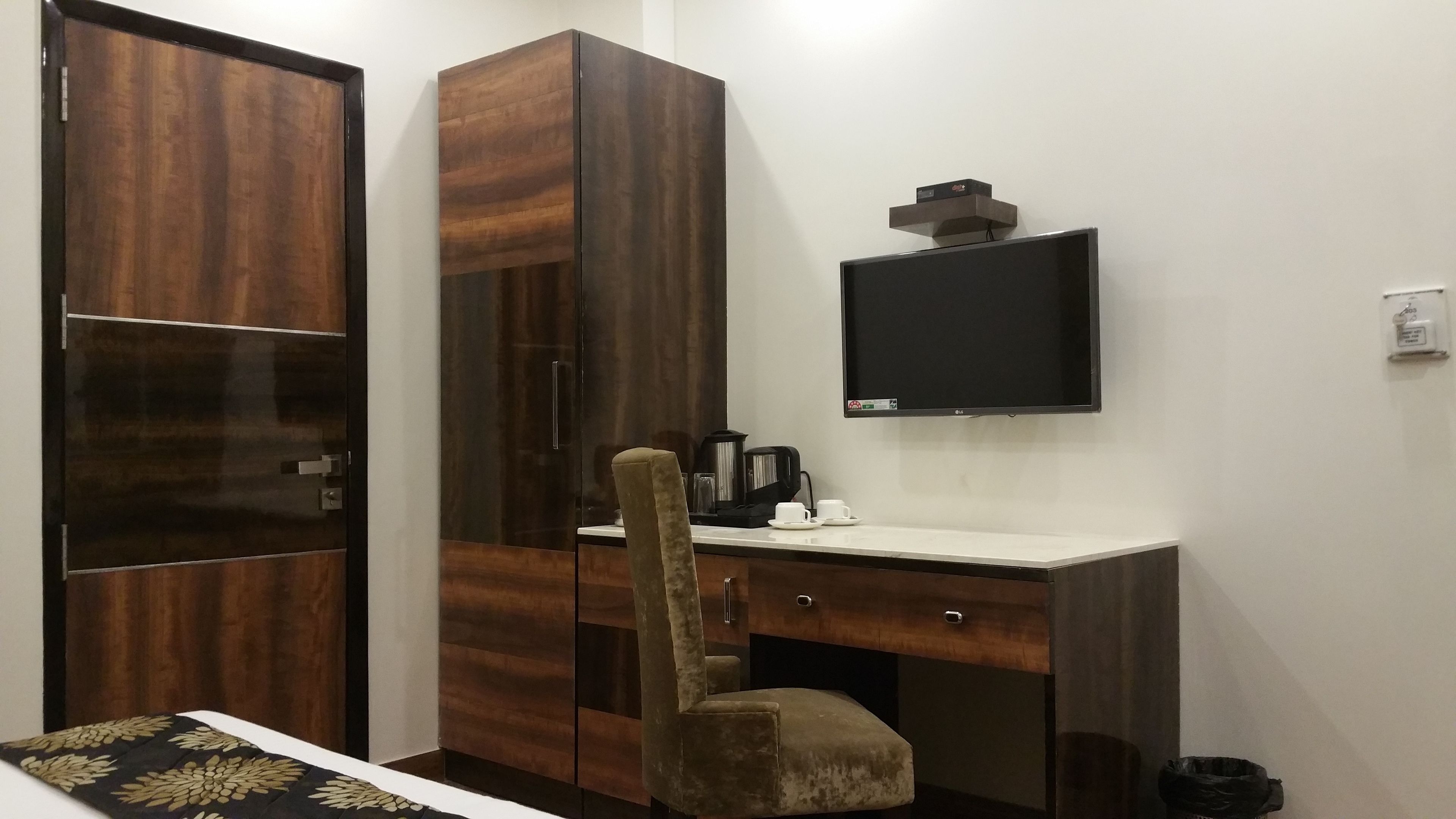 Habitación de hotel con armario, escritorio, silla, televisión y cafetera.