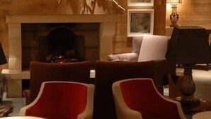 Una habitación acogedora con chimenea, asientos cómodos y una estantería.