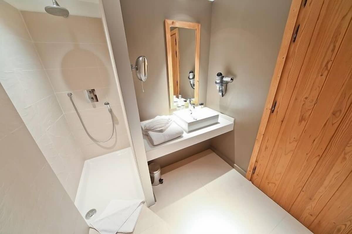 A modern bathroom with a shower, a sink with a mirror, and a wooden door.