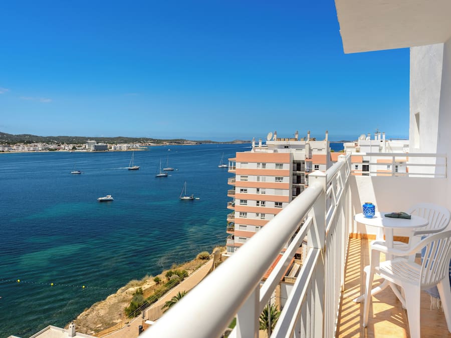 Un balcon avec vue sur la mer, une table avec des chaises et une bouteille.