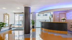 A modern reception area with a curved reception desk, a large mirror, and a potted plant.