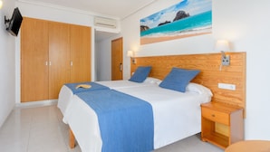 A bedroom with a large bed, wooden wardrobe, and a painting of a beach scene.