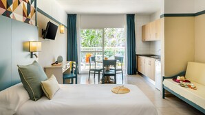 Habitación de hotel con cama, escritorio, silla, televisor y vistas al exterior.