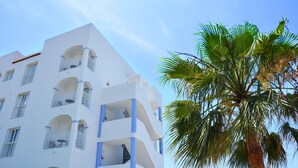 A white building with multiple balconies and a palm tree in the foreground. - Aparthotel Vibra San Marino (Sant Josep de sa Talaia)