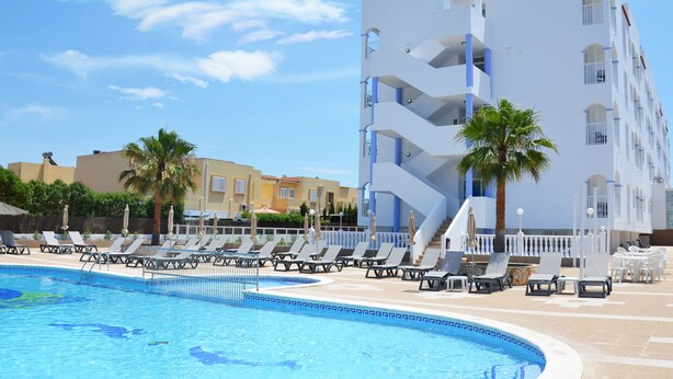 A swimming pool with lounge chairs and palm trees, surrounded by a modern building with balconies. - Aparthotel Vibra San Marino (Sant Josep de sa Talaia)