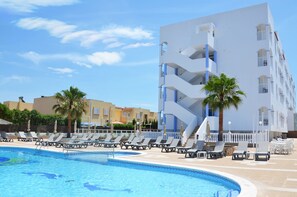 A swimming pool with lounge chairs and palm trees, surrounded by a modern building with balconies. - Aparthotel Vibra San Marino (Sant Josep de sa Talaia)