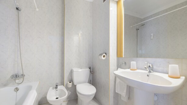 A modern bathroom with a bathtub, bidet, toilet, and sink. - Aparthotel Vibra San Marino (Sant Josep de sa Talaia)
