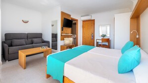 A modern hotel room with a bed, a sofa, a coffee table, a TV, and a bathroom visible through an open door. - Aparthotel Vibra San Marino (Sant Josep de sa Talaia)