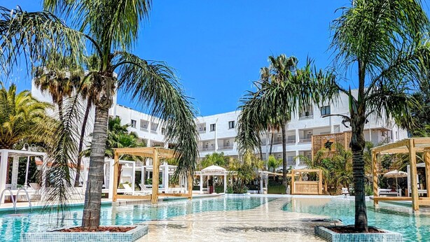 A swimming pool surrounded by palm trees and white buildings with balconies. - The Palm Star Ibiza - Adults Only (Sant Josep de sa Talaia)