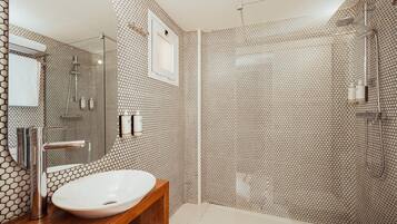 Un baño moderno con un diseño de baldosas hexagonales, un lavamanos redondo, un espejo y una cabina de ducha.