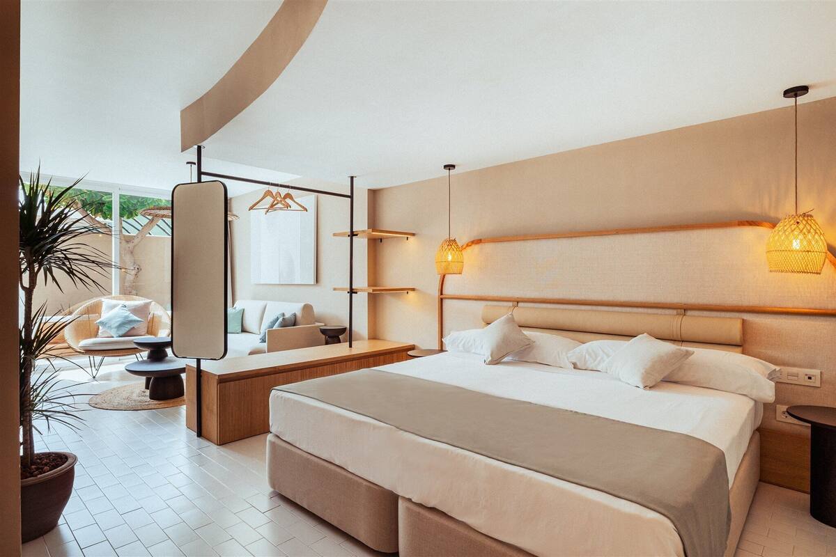 A modern bedroom with a large bed, bedside tables, a mirror, and a hanging light fixture.