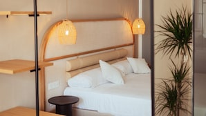 A neatly arranged bedroom with a bed, bedside tables, and hanging lamps. - AMA Ibiza Suites - Adults Only (Sant Josep de sa Talaia)