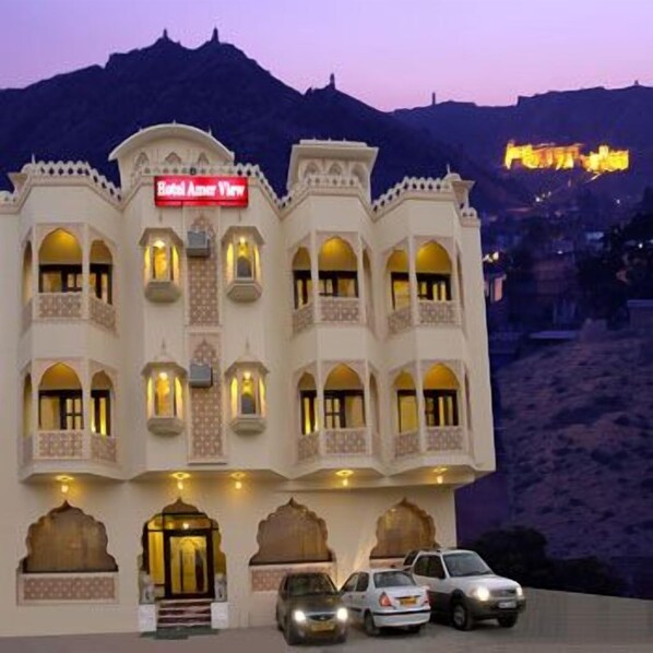A hotel with a sign reading "Hotel Amar View" and a mountainous backdrop.
