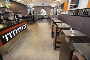Interior moderno de restaurante com área de bar, disposição de mesas e vista pela janela.