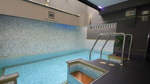 Una piscina interior con paredes de azulejos y un suelo azul cristalino.