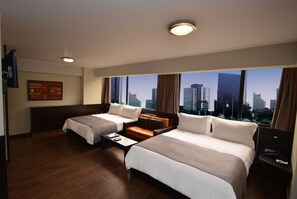 A hotel room with two beds, a sofa, a TV, and a large window with a city view. - qp Hotels Lima (Lima)