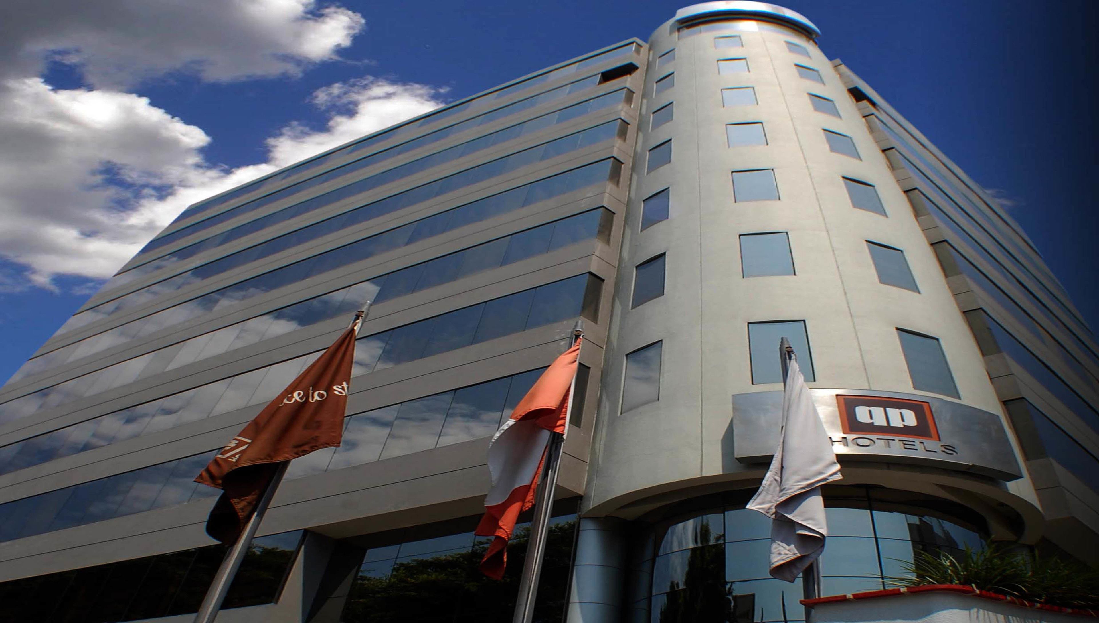 Un hôtel moderne à la façade incurvée, doté de grandes fenêtres et d’une enseigne « HÔTELS » bien visible.
