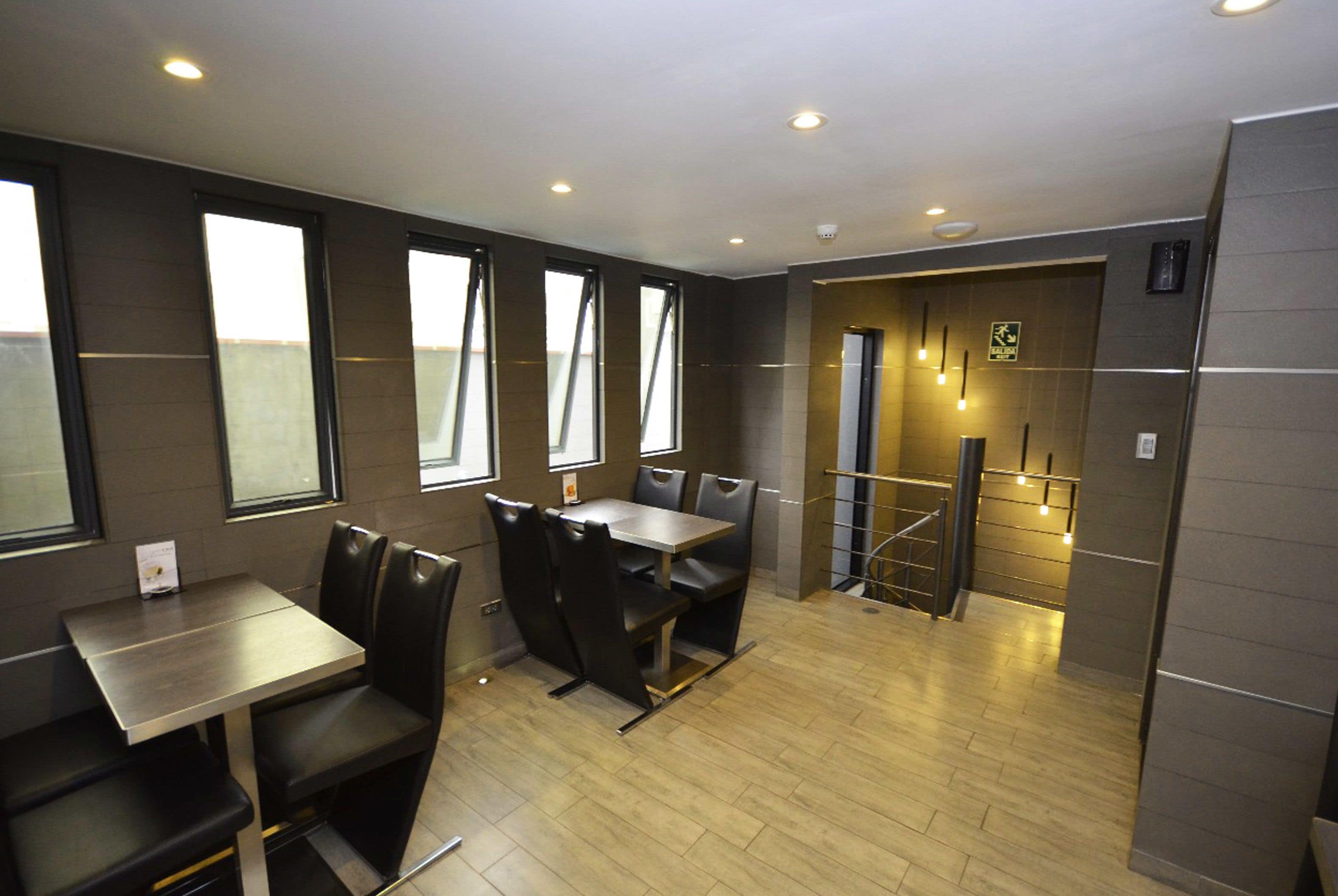 A modern dining area with a table and chairs, large windows, and a view of the sky.