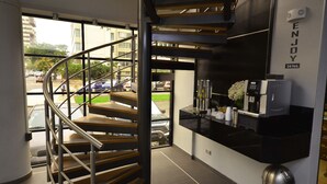 Un interior moderno con una escalera espiral, una estación de café y vistas a la calle.