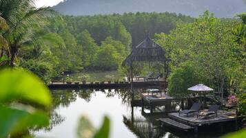A tranquil lakeside setting with a wooden gazebo, lounge chairs, and a dock extending into the water.