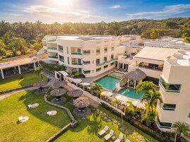 Un hotel moderno con varios pisos, piscina y zonas de estar al aire libre.