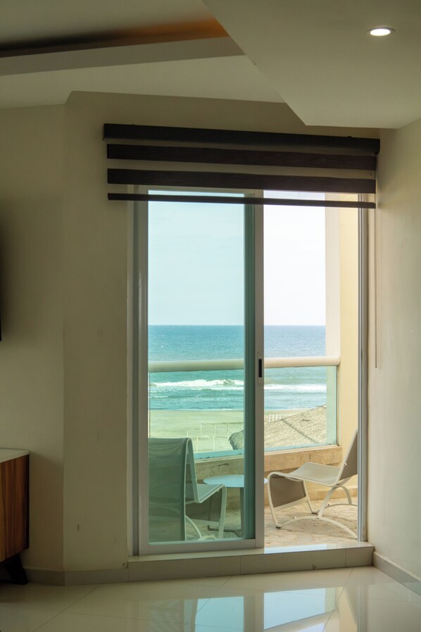 A room with a large sliding glass door leading to a beach view.