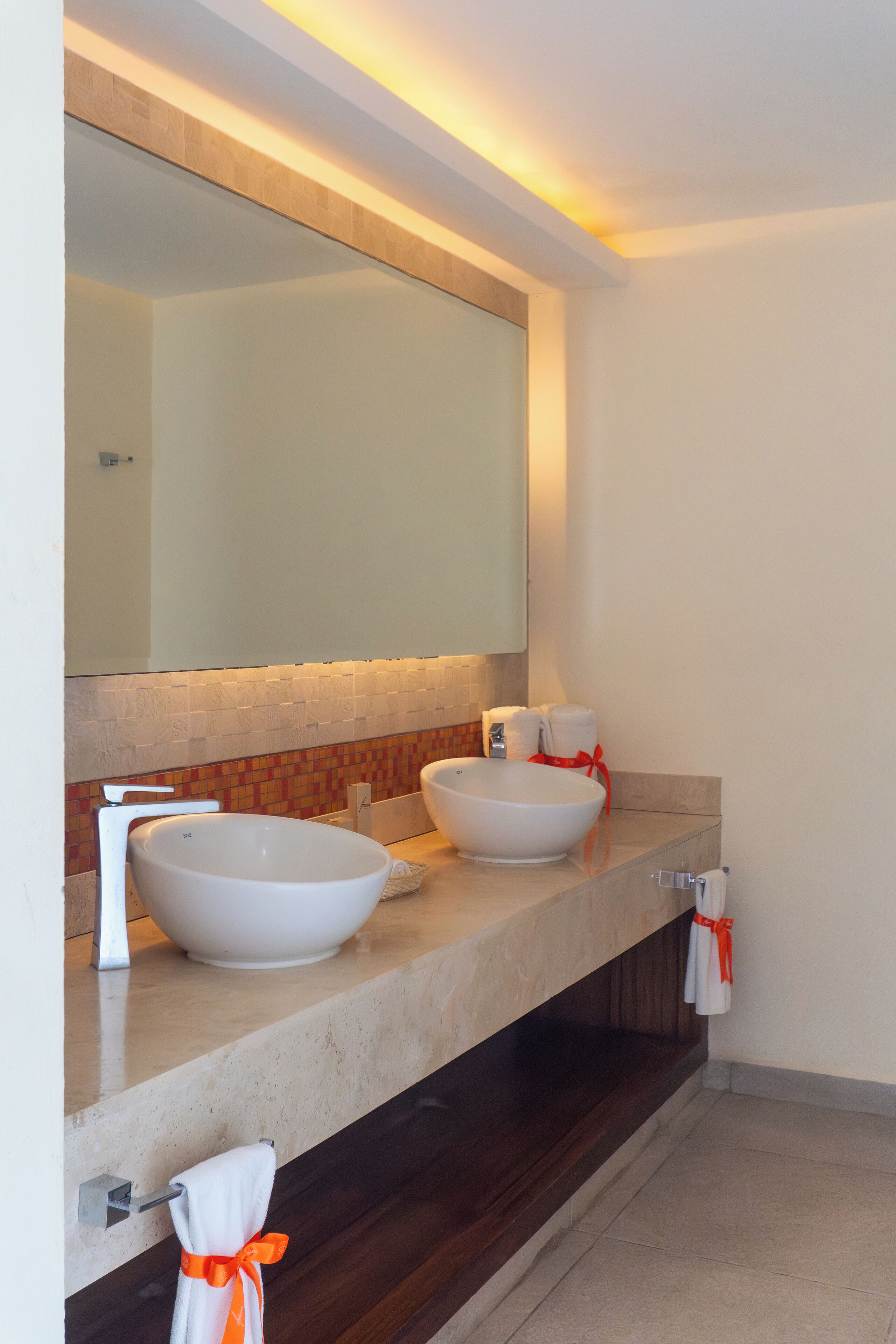 Un baño moderno con dos lavamanos grandes, un espejo y un perchero para toallas.