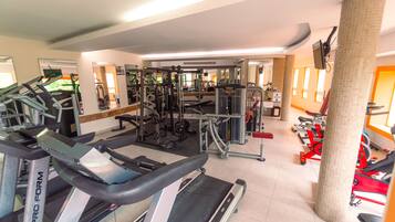 Ein Fitnessstudio mit Laufbändern, Kraftgeräten und einer Spiegelwand.