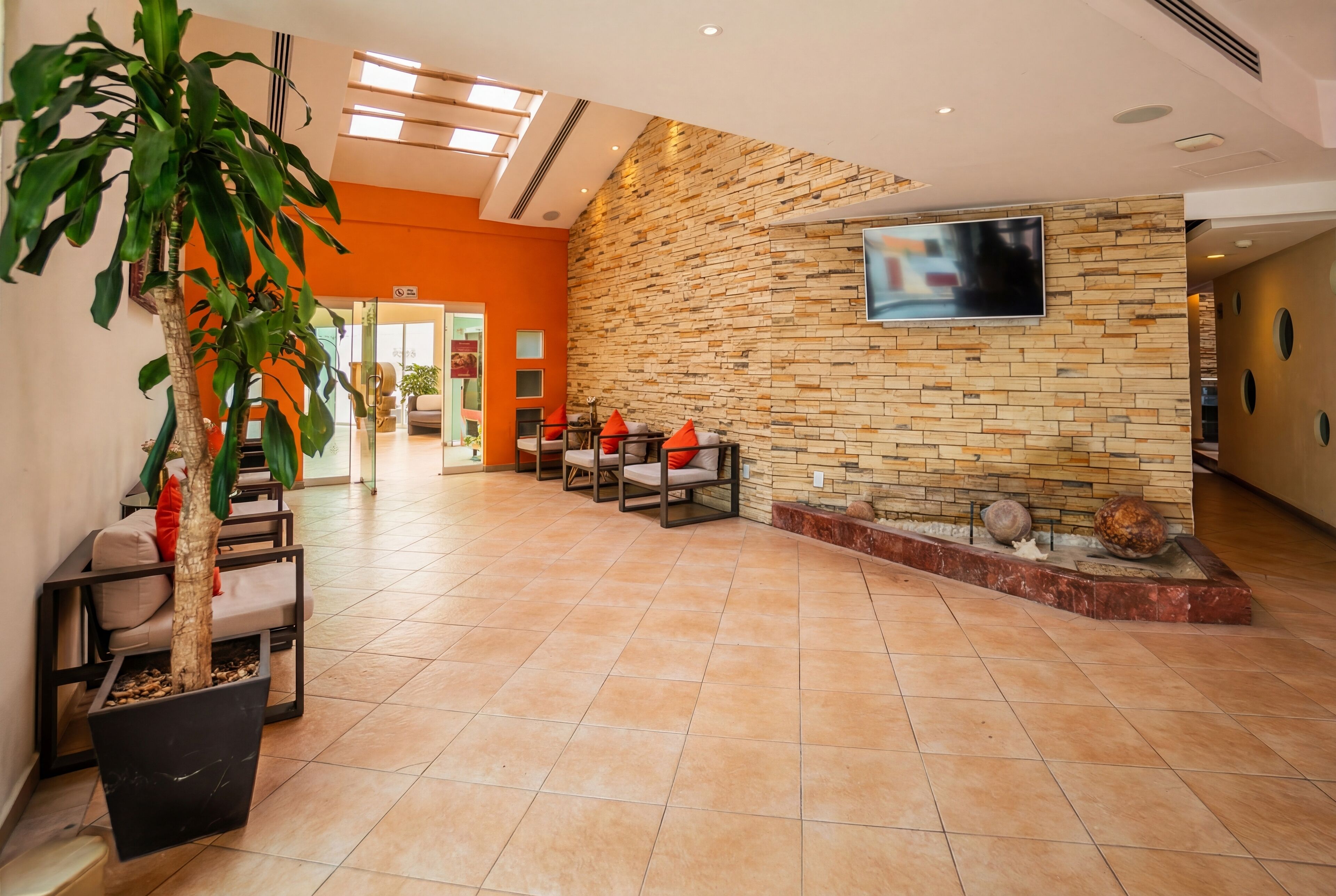 A lobby with a stone wall, a TV mounted on it, and a reception desk.