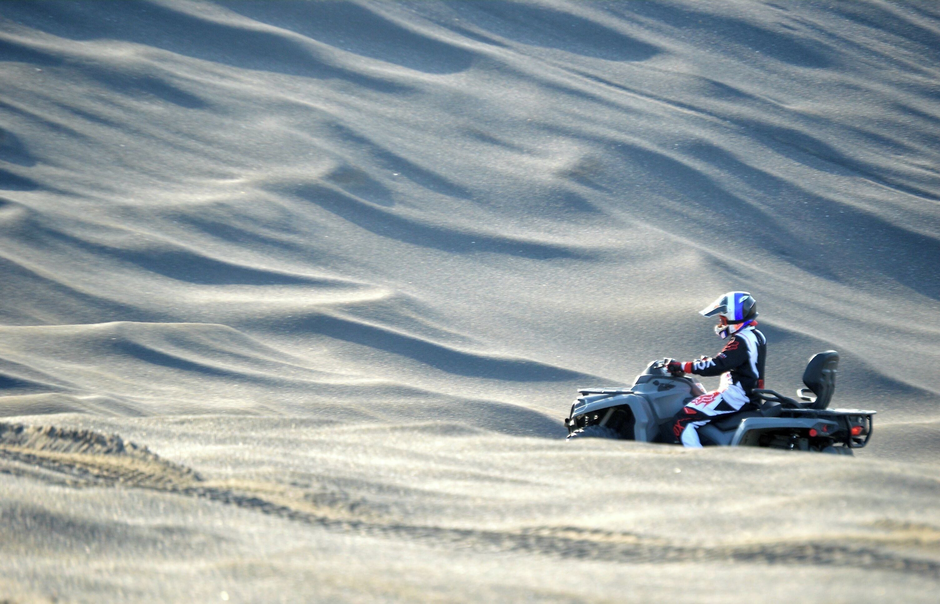 Eine Person fährt mit einem Quad über sandiges Gelände.