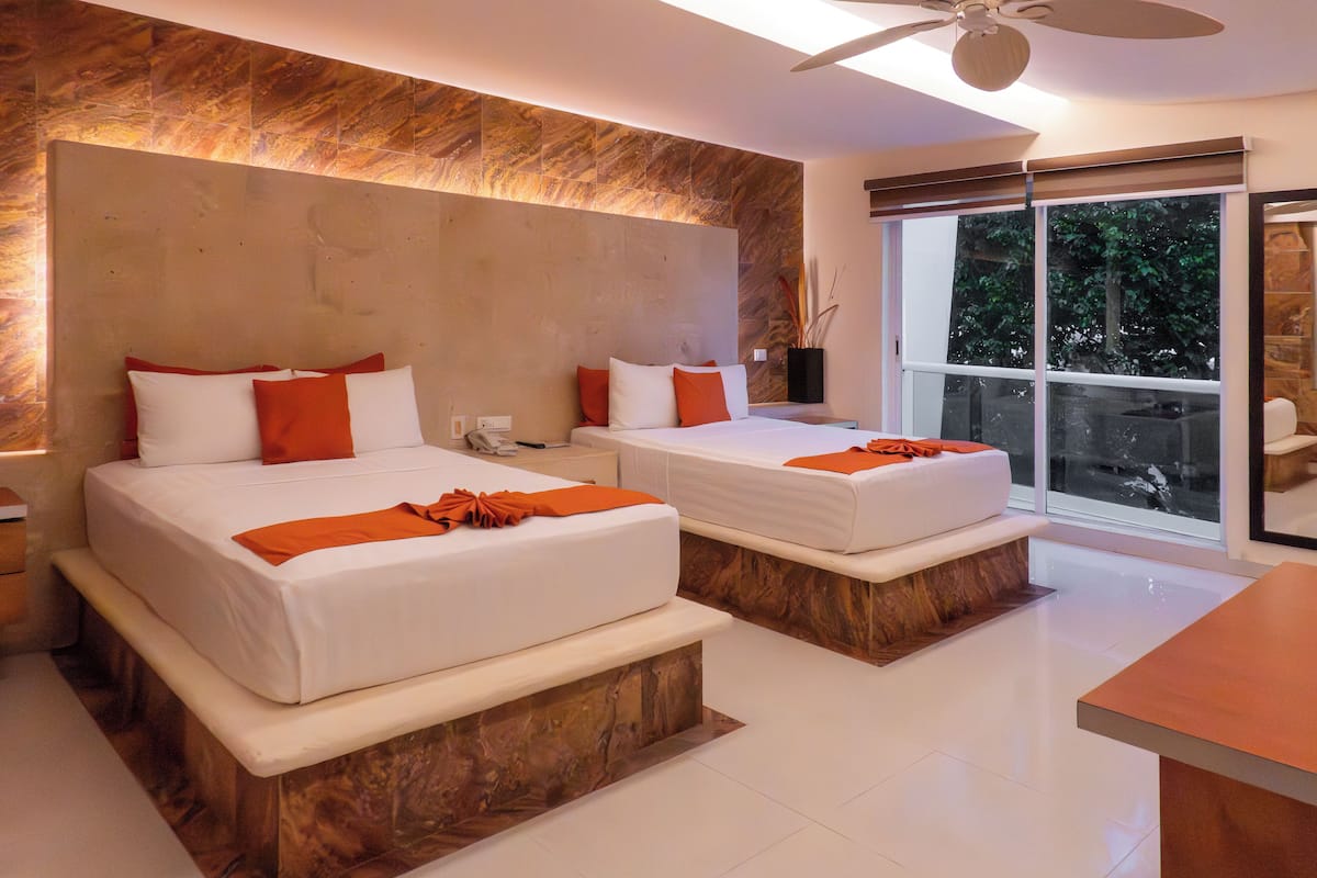 Una habitación de hotel moderna con dos camas, un ventanal grande y un ventilador de techo.