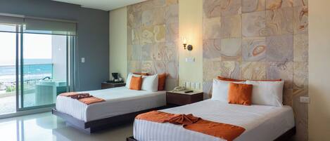 A hotel room with two beds, a large window with a view of the ocean, a ceiling fan, and a stone-patterned wall.