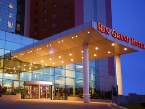 A modern hotel entrance with a glass facade, a covered entrance area, and a prominent hotel sign.