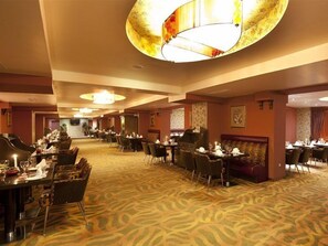 Un comedor de hotel con varias mesas, sillas y un piano de cola.