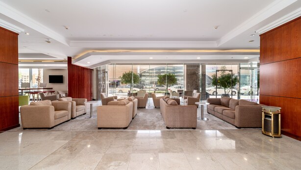 Eine geräumige Lobby mit mehreren Sitzbereichen, einem großen Fenster mit Blick auf die Stadt und einem modernen Interior-Design.