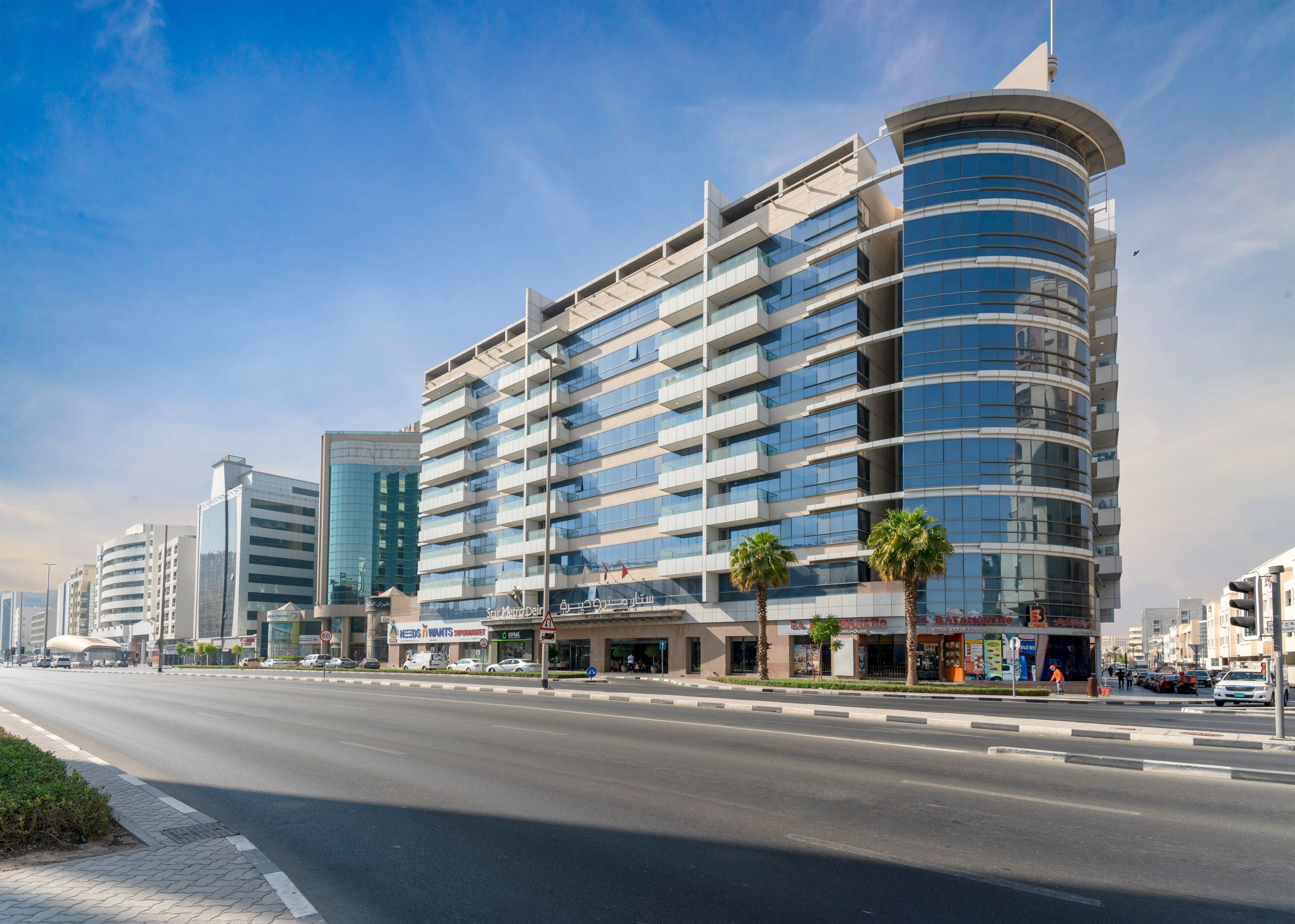 A modern multi-story hotel with a curved facade, large windows, and a prominent corner entrance.
