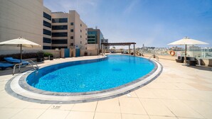Ein Dachpool mit klarem, blauem Wasser, Liegestühlen und Sonnenschirmen.
