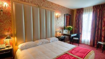 A hotel room with a large bed, a desk, a chair, and a mirror.